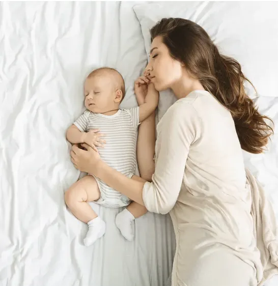 Mother and baby sleeping together in a safe cosleeping setup